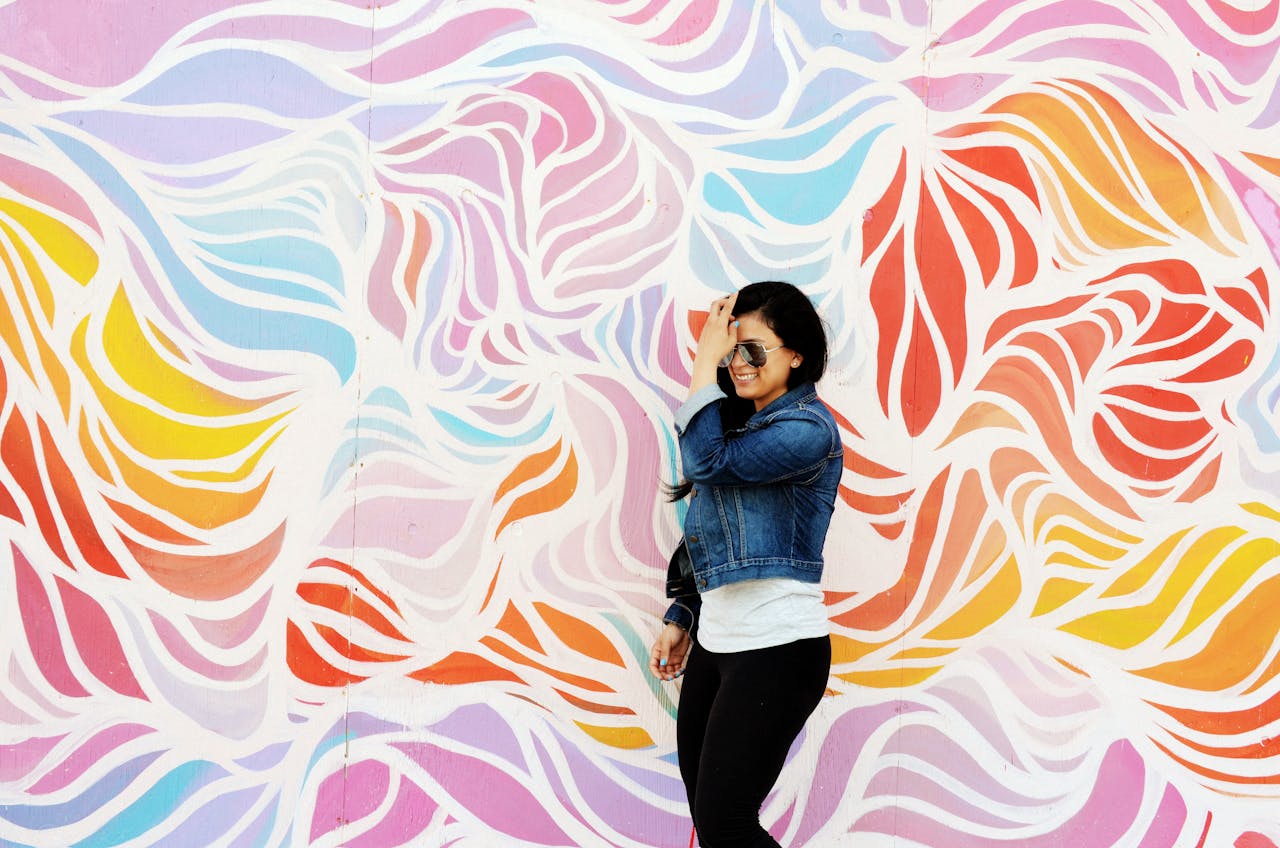 services-01 A woman in a denim jacket poses joyfully against a vibrant mural in Asbury Park, NJ.